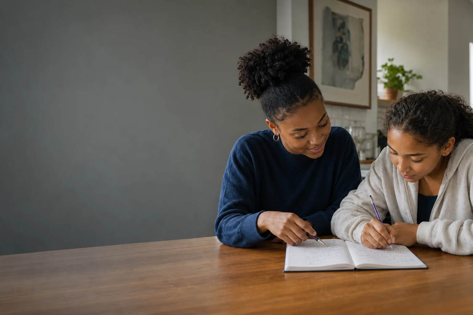 A young tutor helping a high-school learner work through a maths problem at home