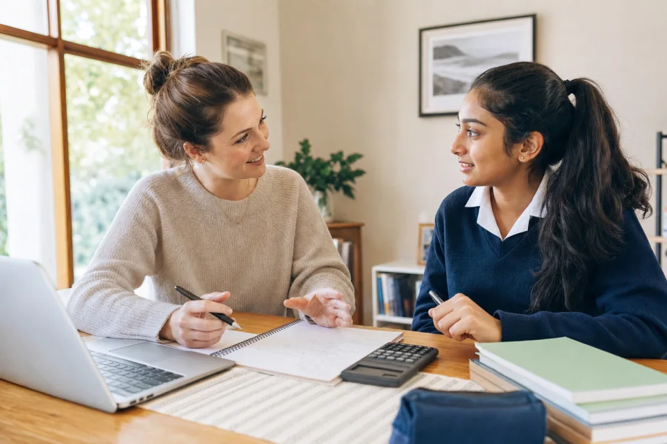 A female tutor helping a female high-school learner with maths at home